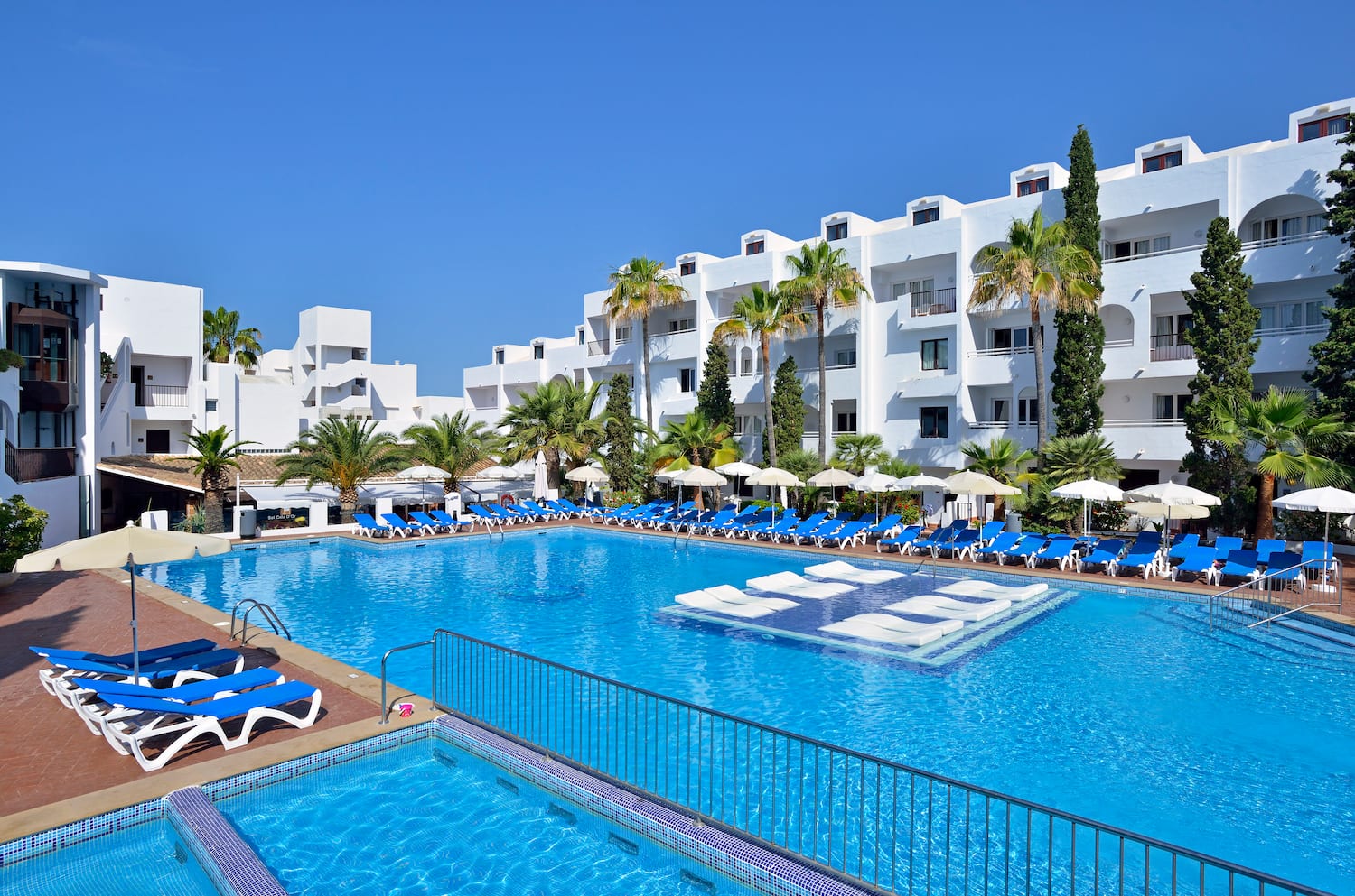 a pool with lounge chairs and a building in the background