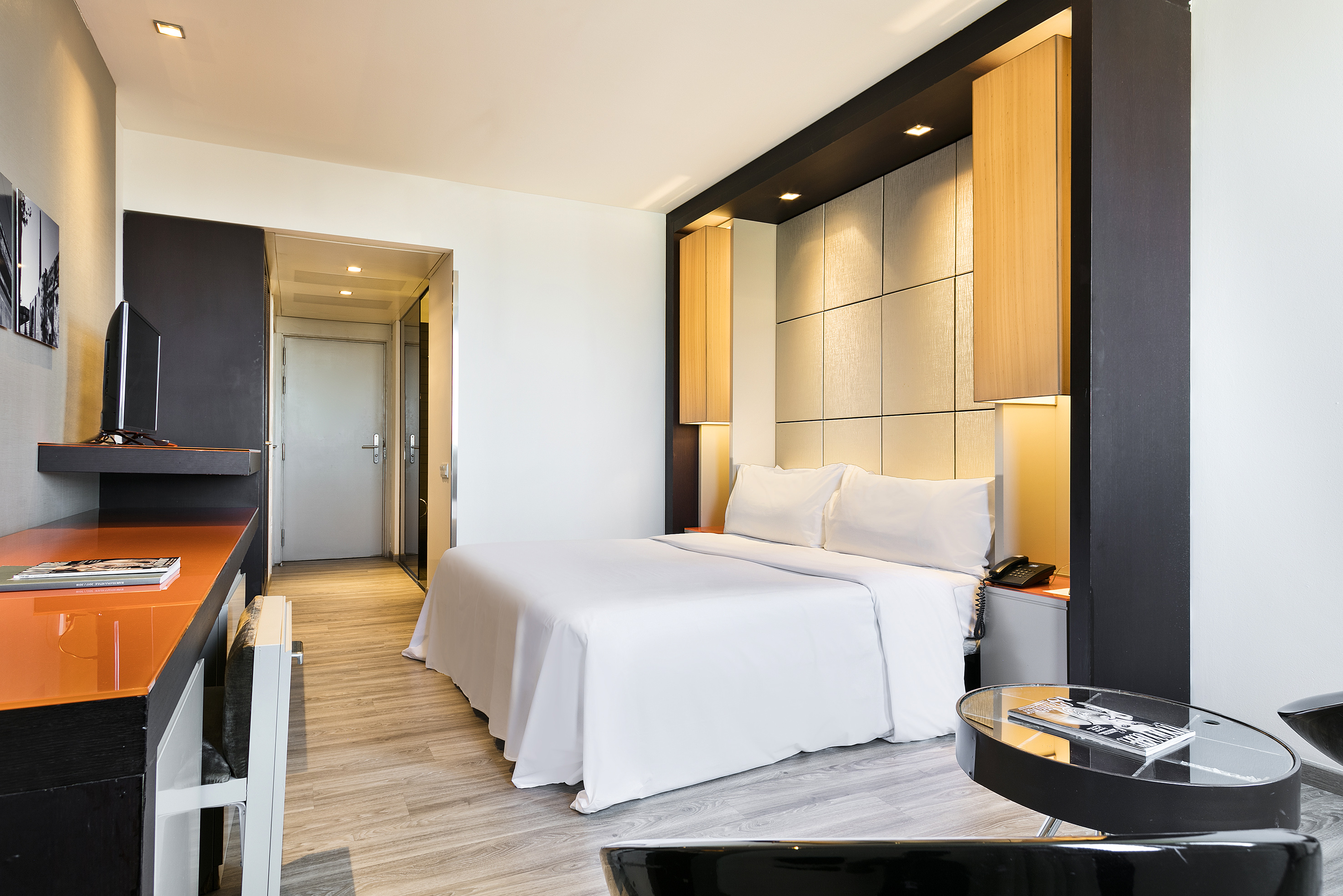 Modern hotel guest room with king bed, sleek desk, and accent lighting.