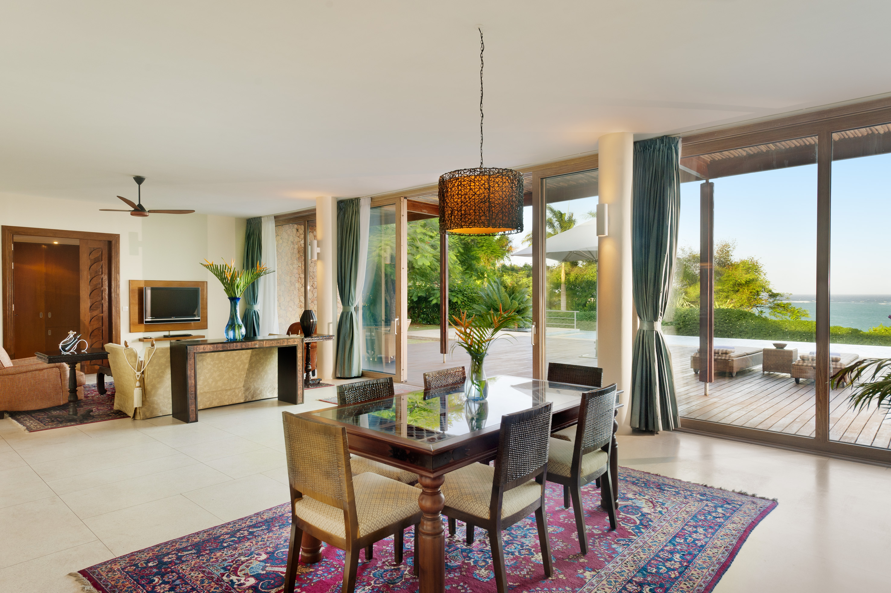 Luxury open-plan living and dining space with ocean view, tropical deck.