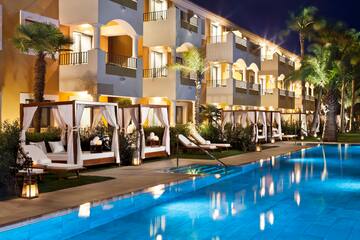 a pool with lounge chairs and a building with trees and lights