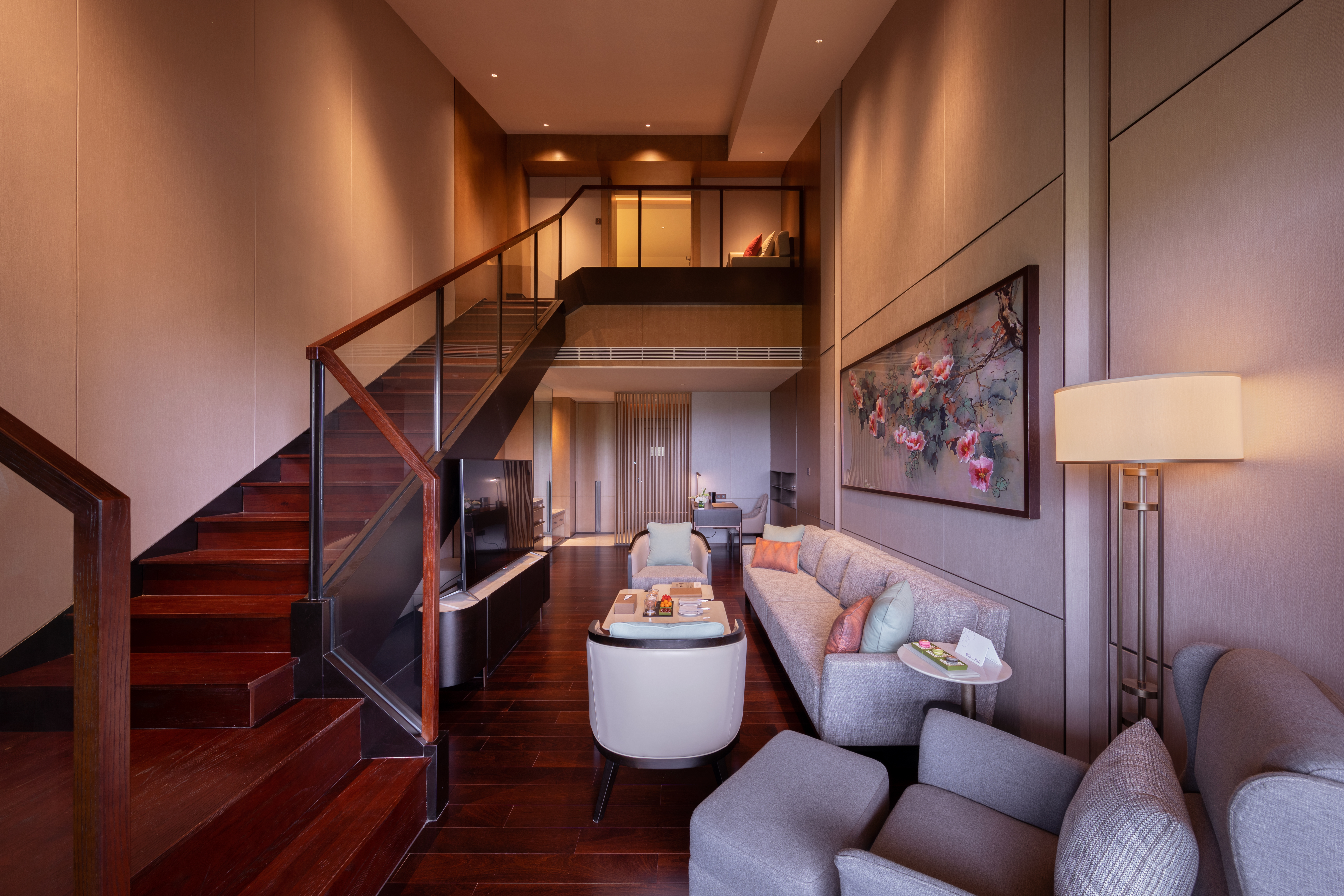 Modern luxury duplex living room with staircase, sofa, and floral artwork.