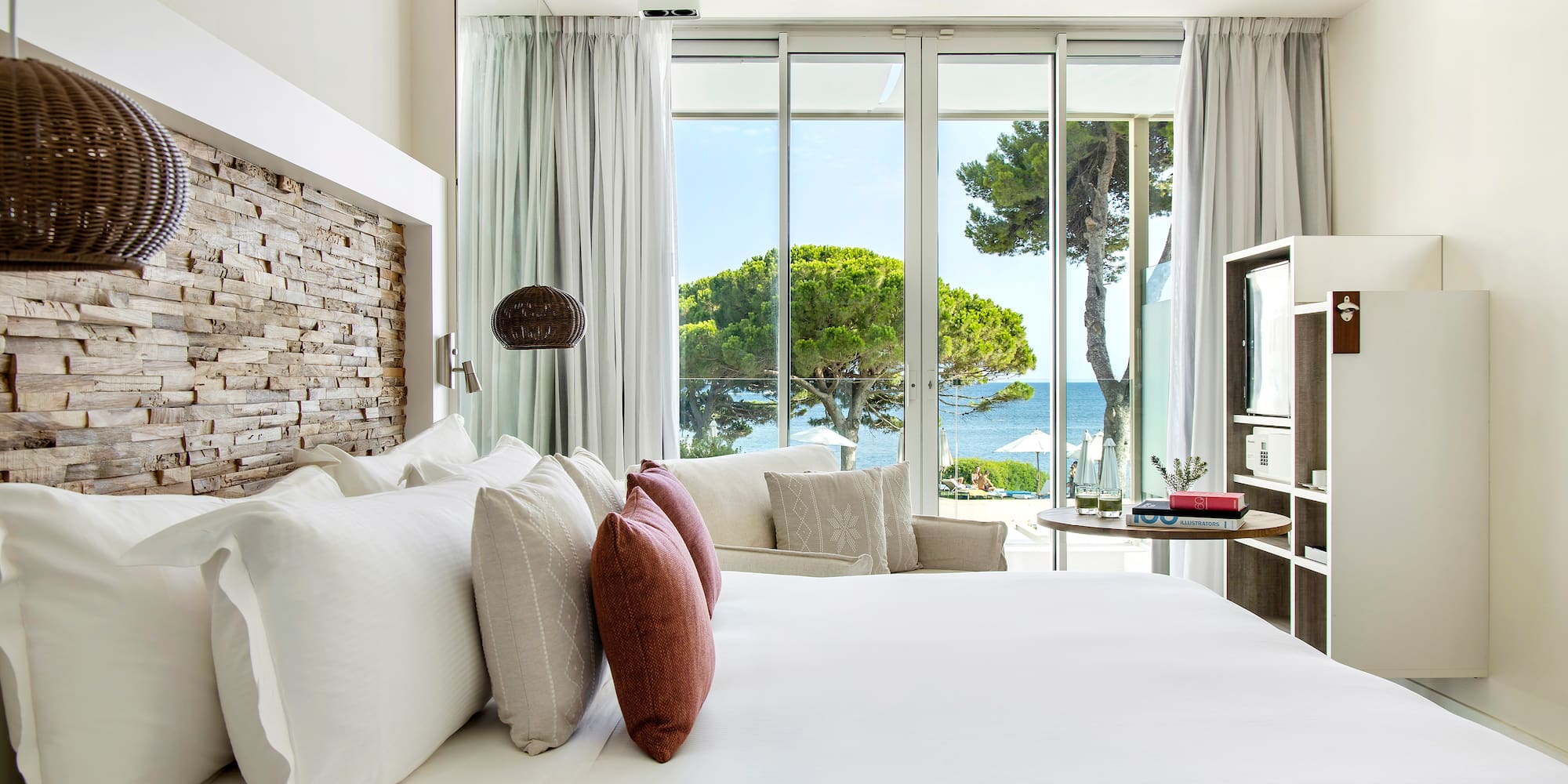a bed with pillows and a fireplace in a room with a view of the ocean