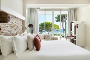 a bed with pillows and a fireplace in a room with a view of the ocean