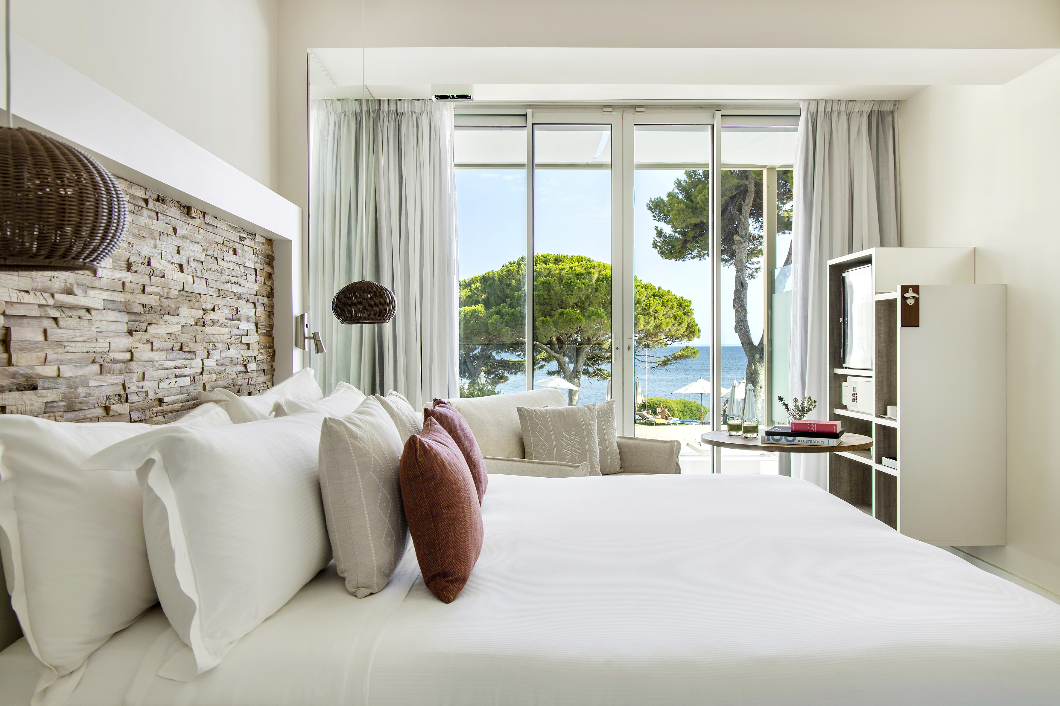 a bed with pillows and a fireplace in a room with a view of the ocean