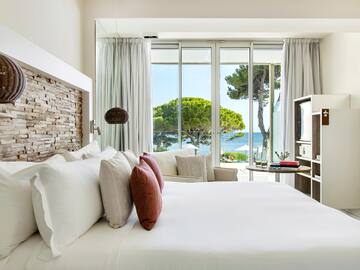 a bed with pillows and a fireplace in a room with a view of the ocean