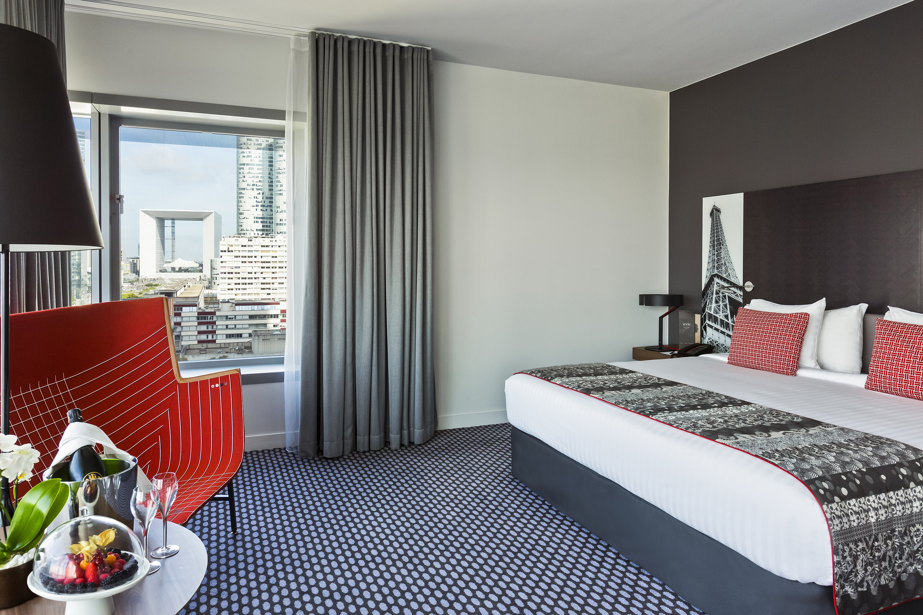 Modern hotel room with king bed, La Défense city view, and champagne.