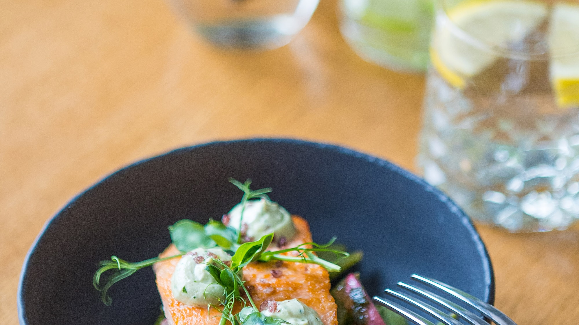 a bowl of food with a fork and a glass of water