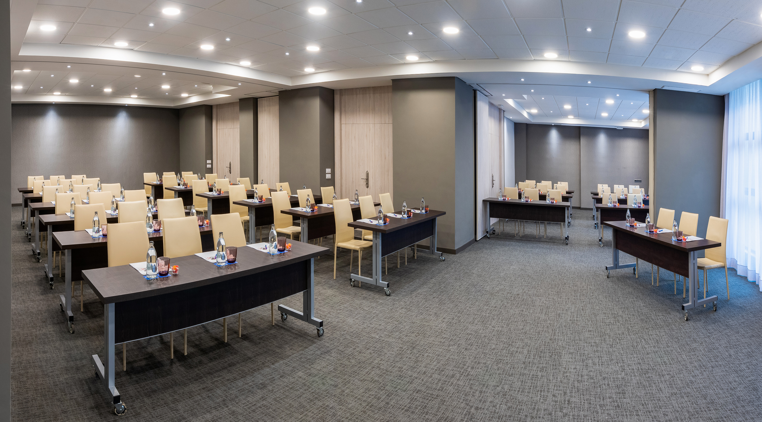 Modern conference room set up with tables, beige chairs, and bottled water.