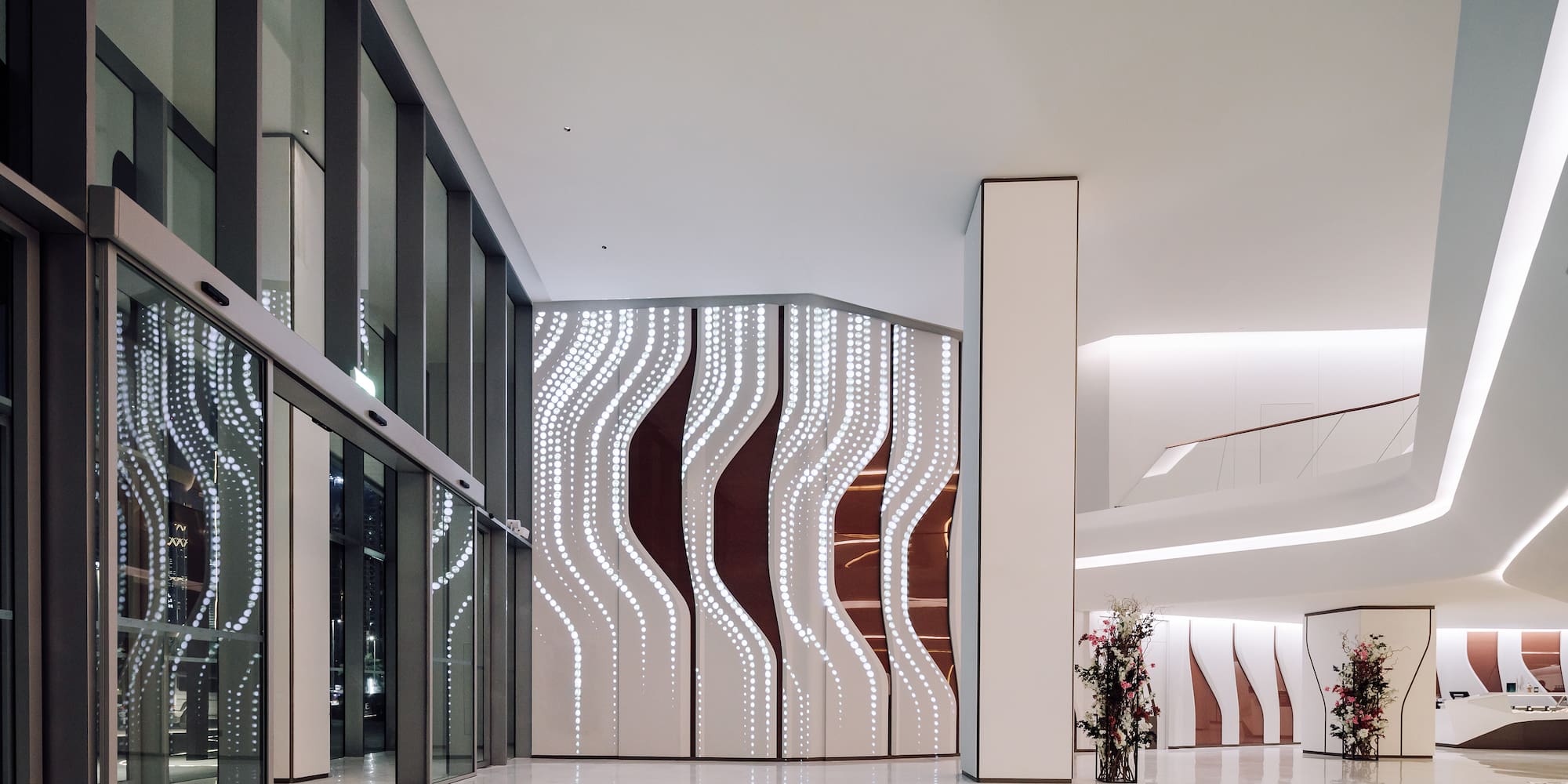 a large white and brown room with glass doors and a vase of flowers