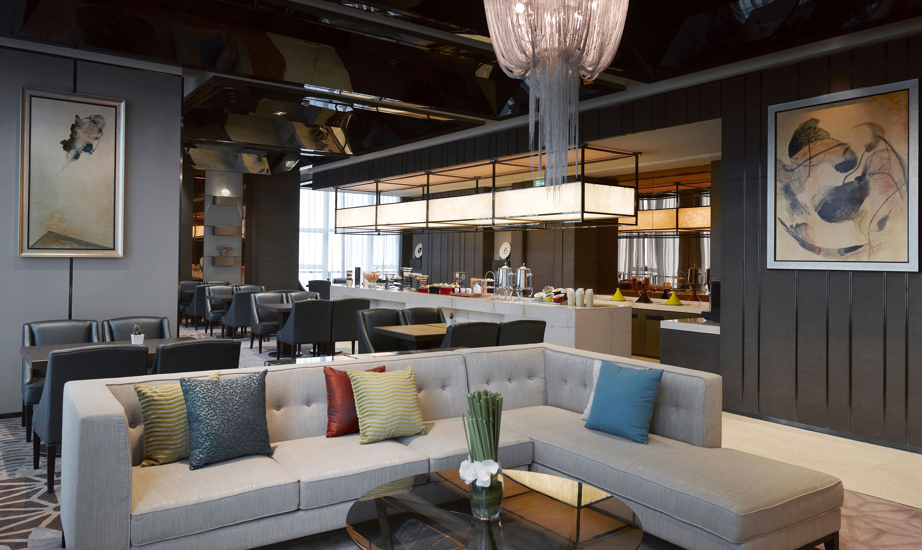 Modern hotel lounge with buffet, sectional sofa, and dining area.