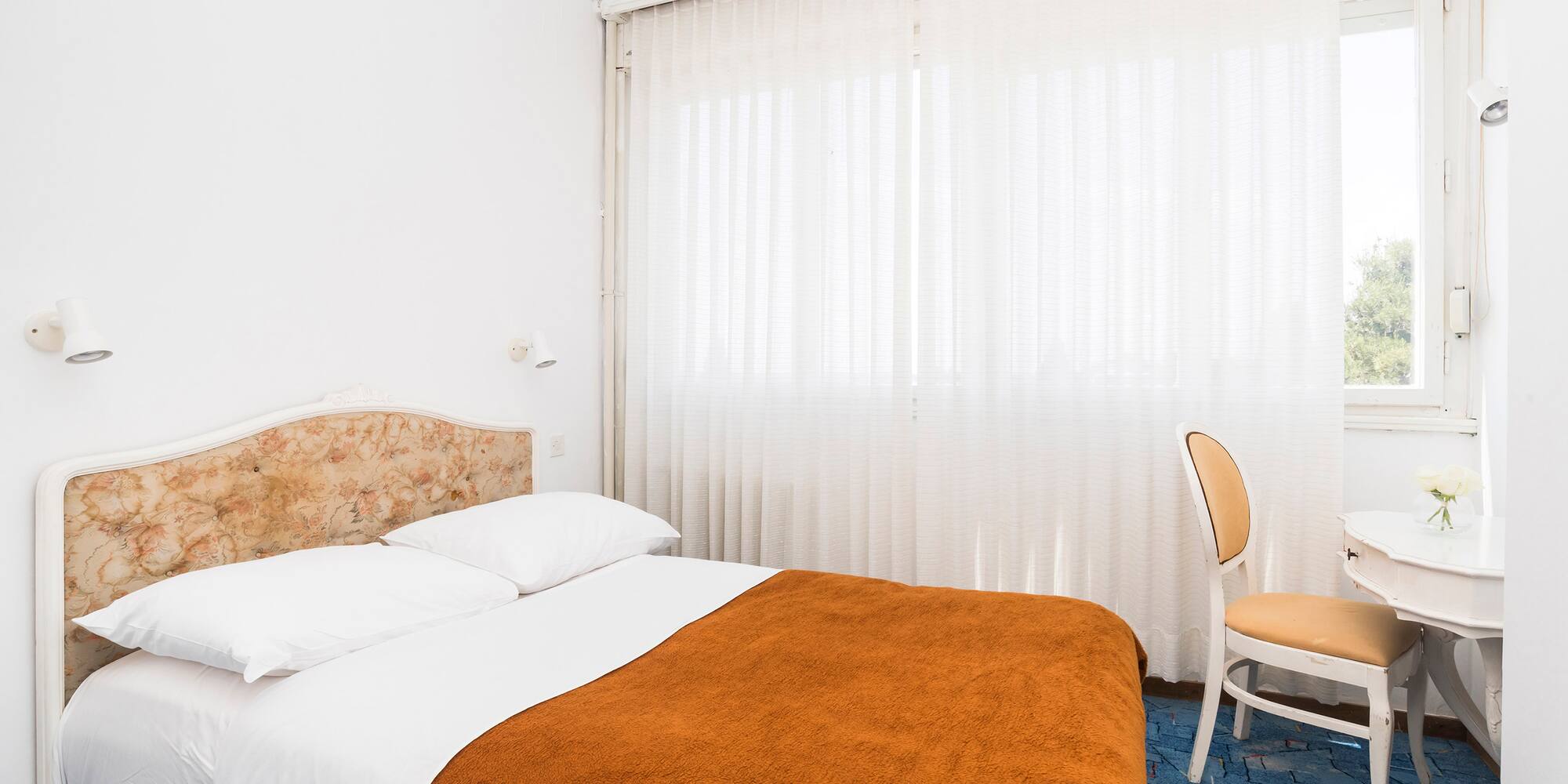 a bed with a chair and a chair in a room