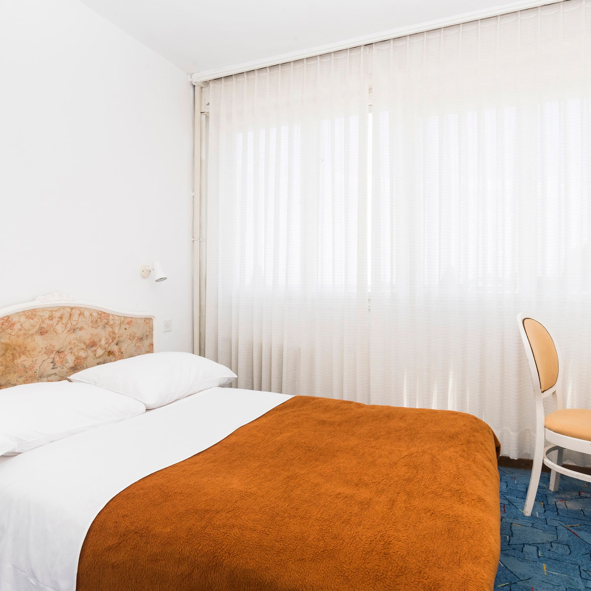 a bed with a chair and a chair in a room