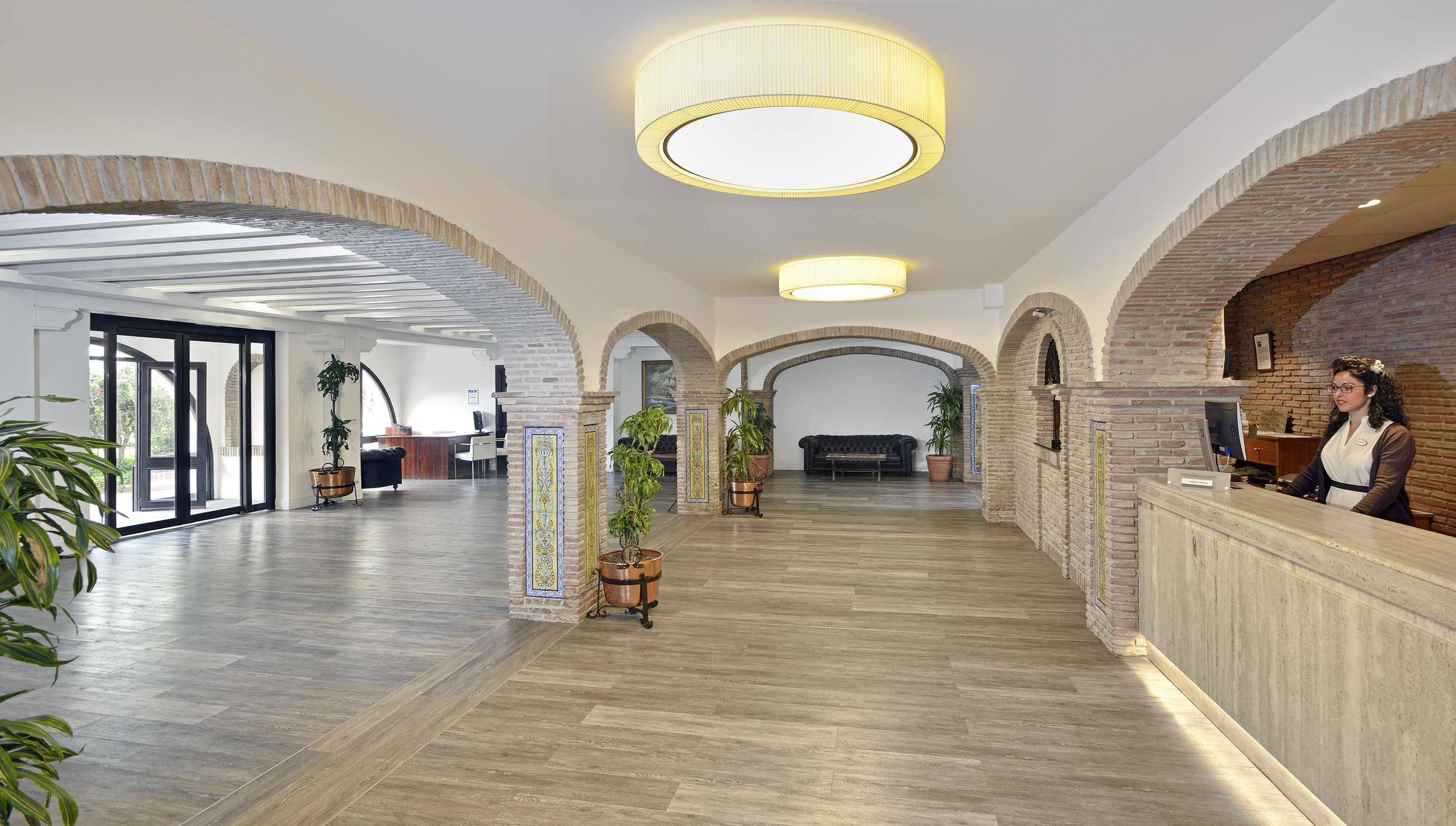 Hotel reception with rustic brick arches, modern lighting, and front desk staff.