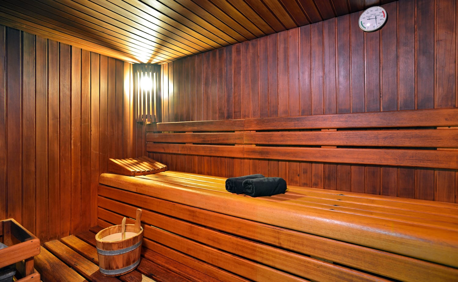 a wooden sauna with a bucket and a towel