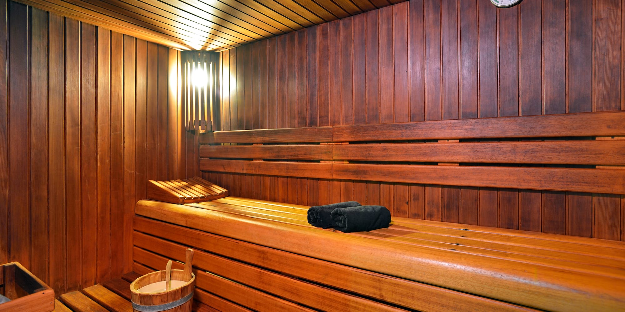 a wooden sauna with a bucket and a towel