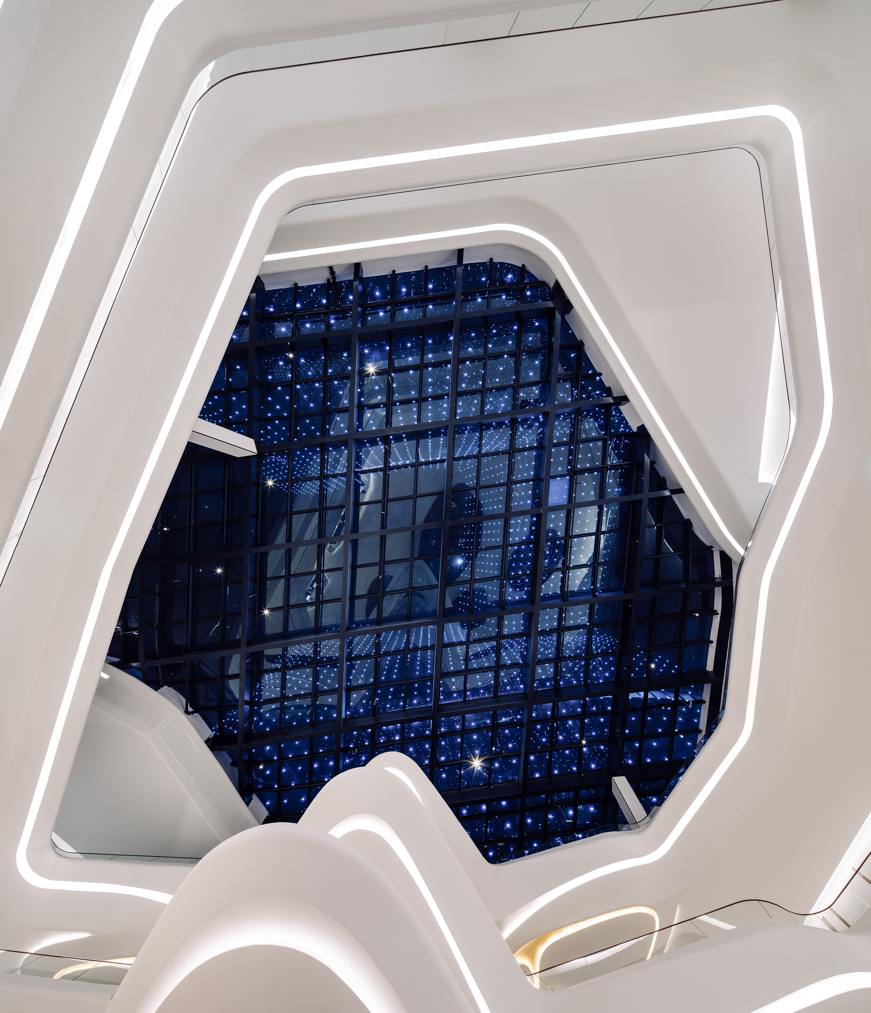 Futuristic white curved architecture with integrated LED lighting and blue starry ceiling.