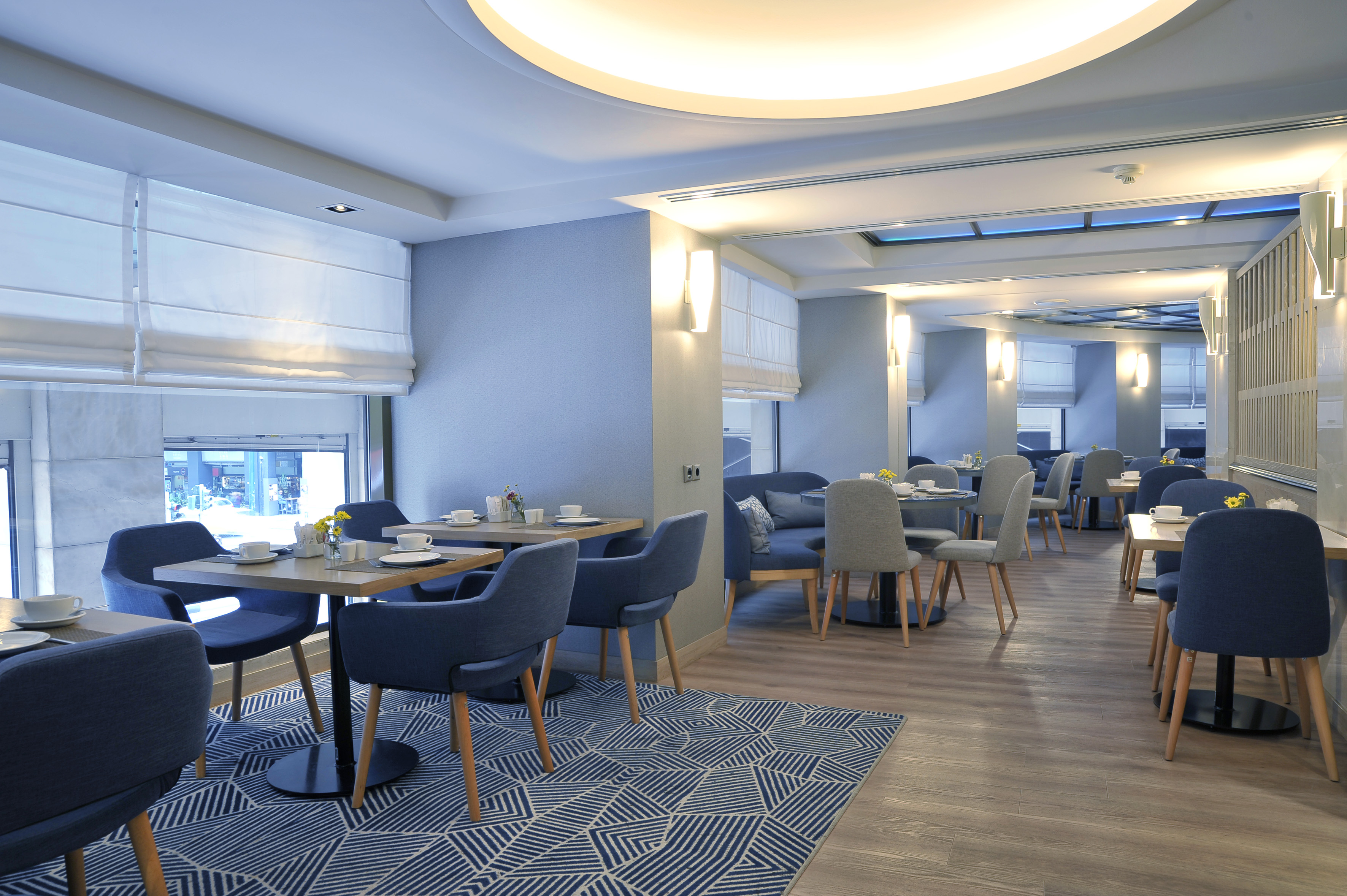 Stylish hotel restaurant interior featuring blue chairs and wooden tables.