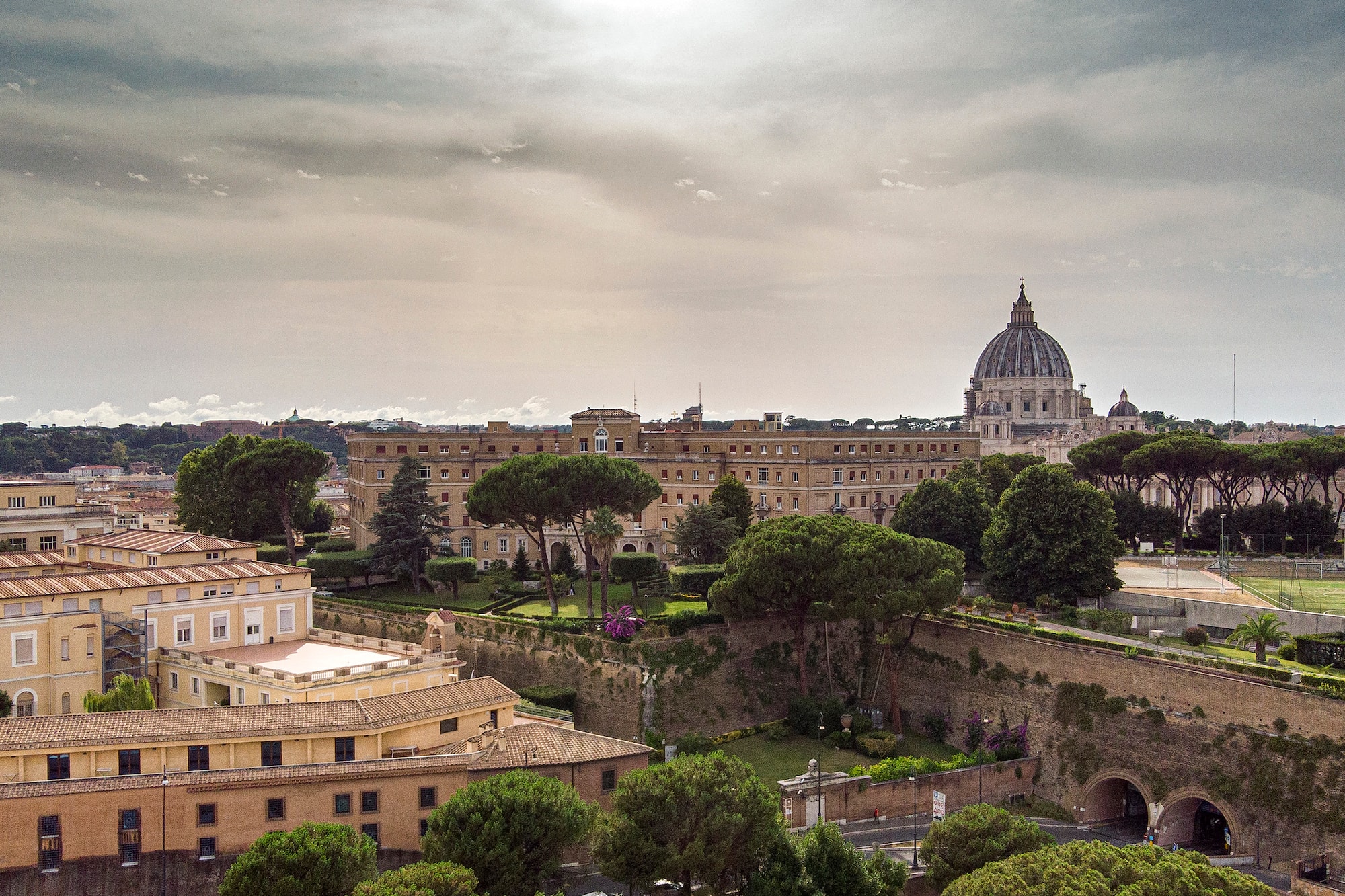 Vatican City cityscape with St. Peter's Basilica, historic buildings, lush gardens.