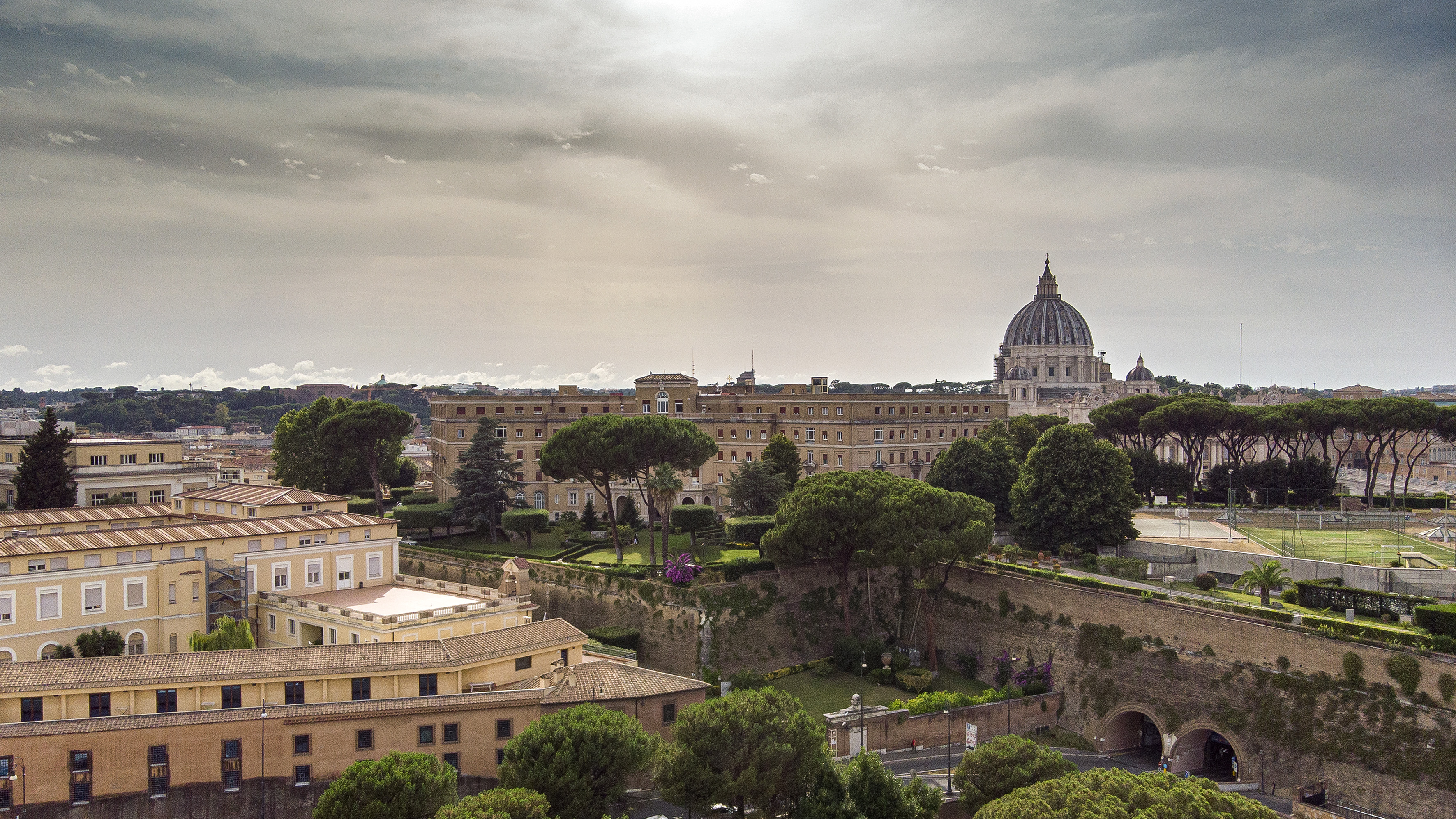 Vatican City cityscape with St. Peter's Basilica, historic buildings, lush gardens.