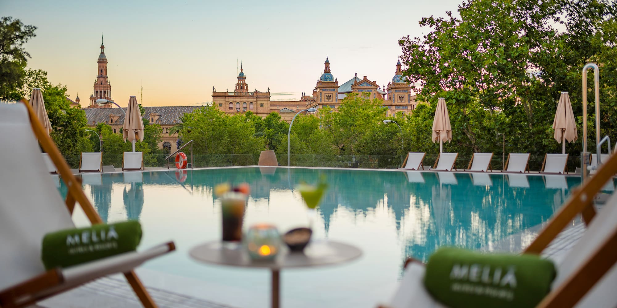 a pool with chairs and a table with a building in the background