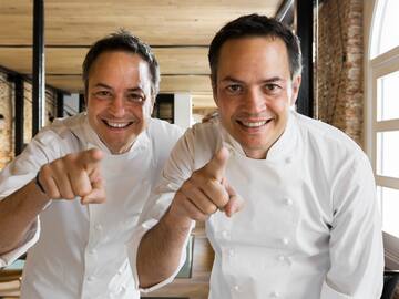 two men wearing white chef jackets pointing at camera