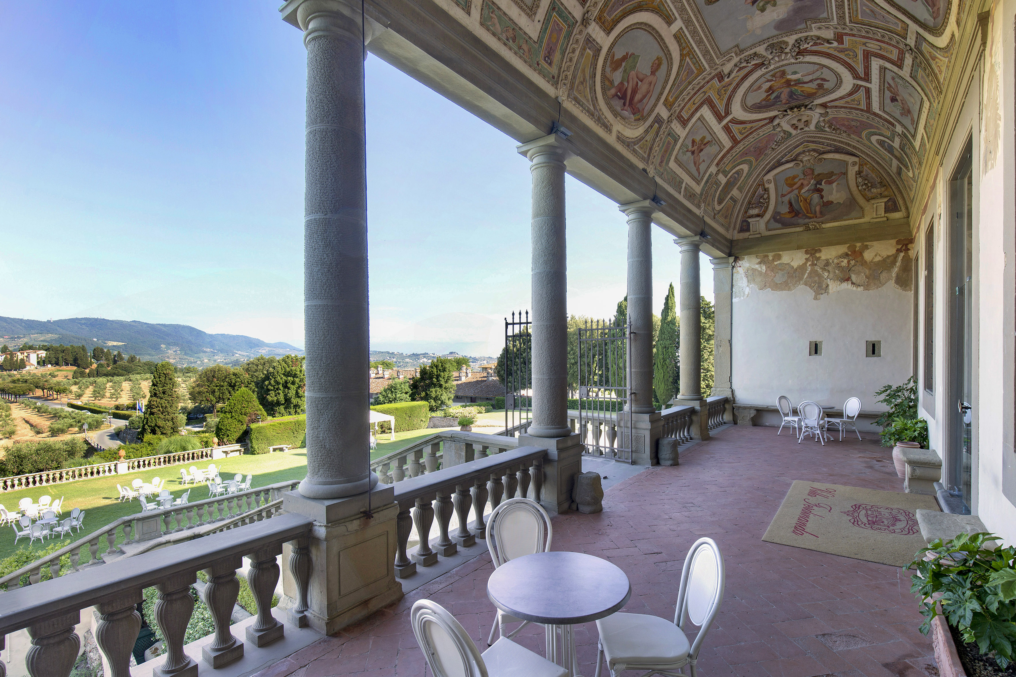Tuscan villa loggia, frescoed ceiling, outdoor dining patio, garden landscape.