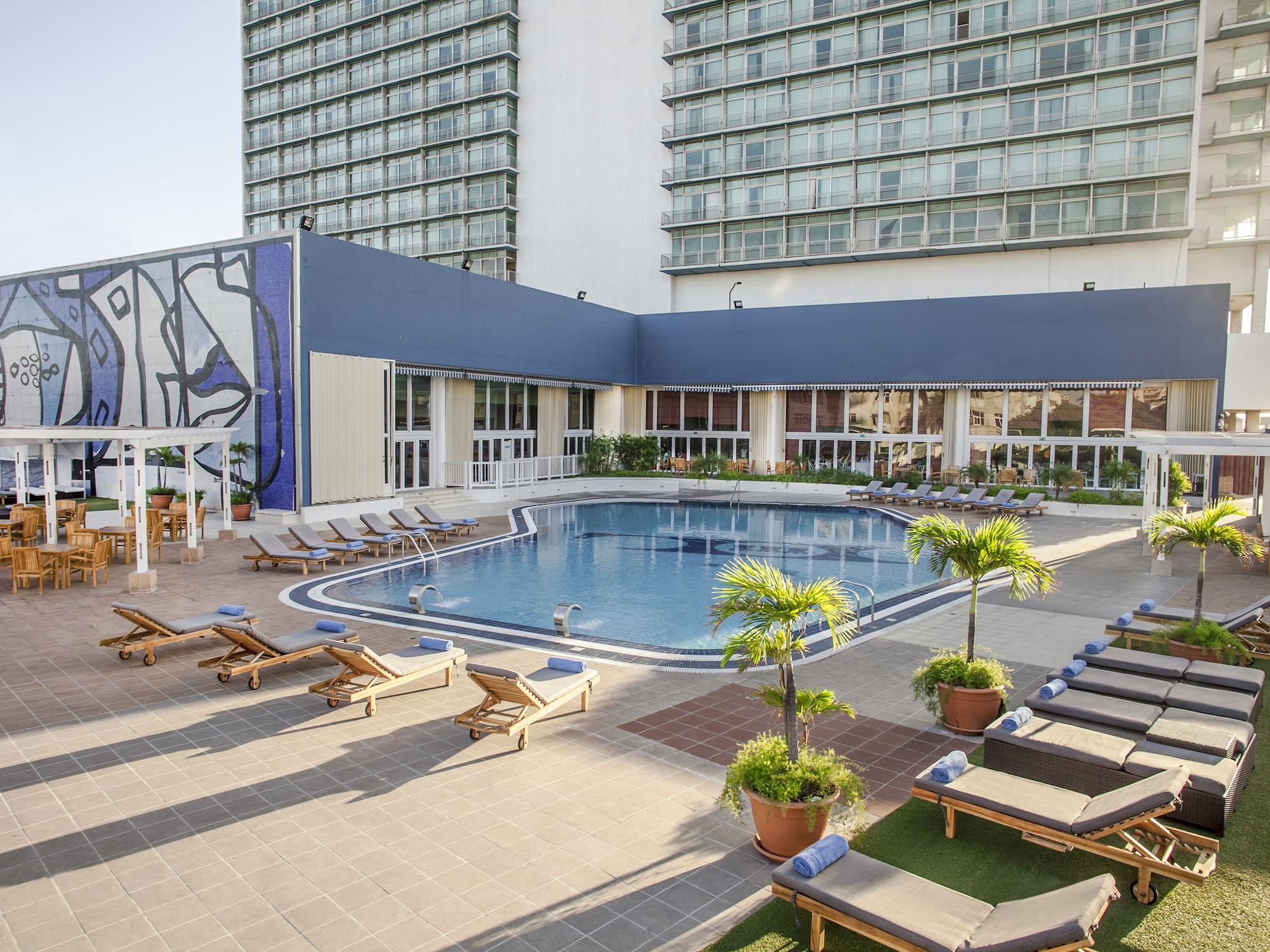a pool with lounge chairs and a building with windows