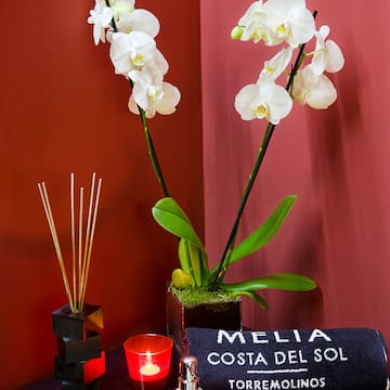 a white orchids in a pot next to a towel and candle