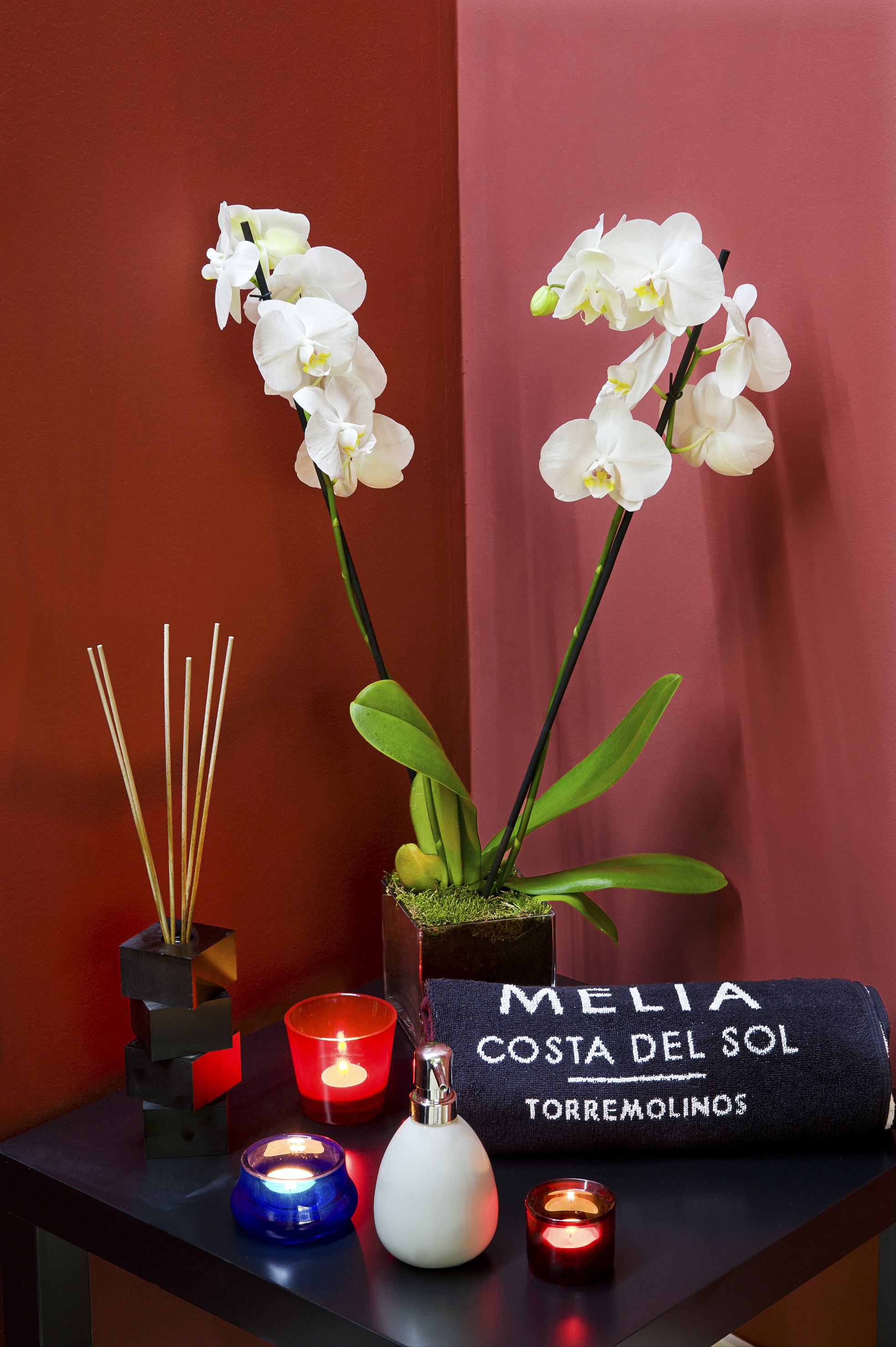 a white orchids in a pot next to a towel and candle