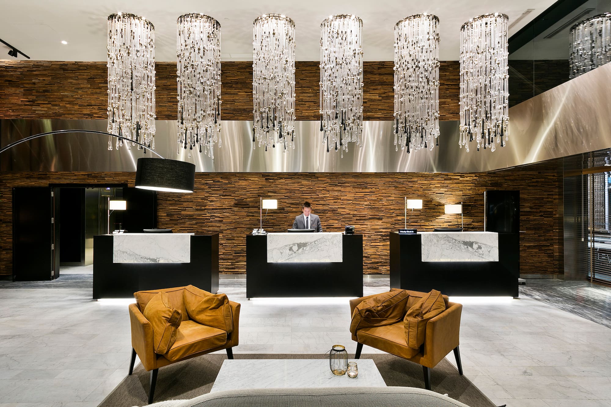 Elegant hotel lobby with crystal chandeliers, wood paneling, and front desk.