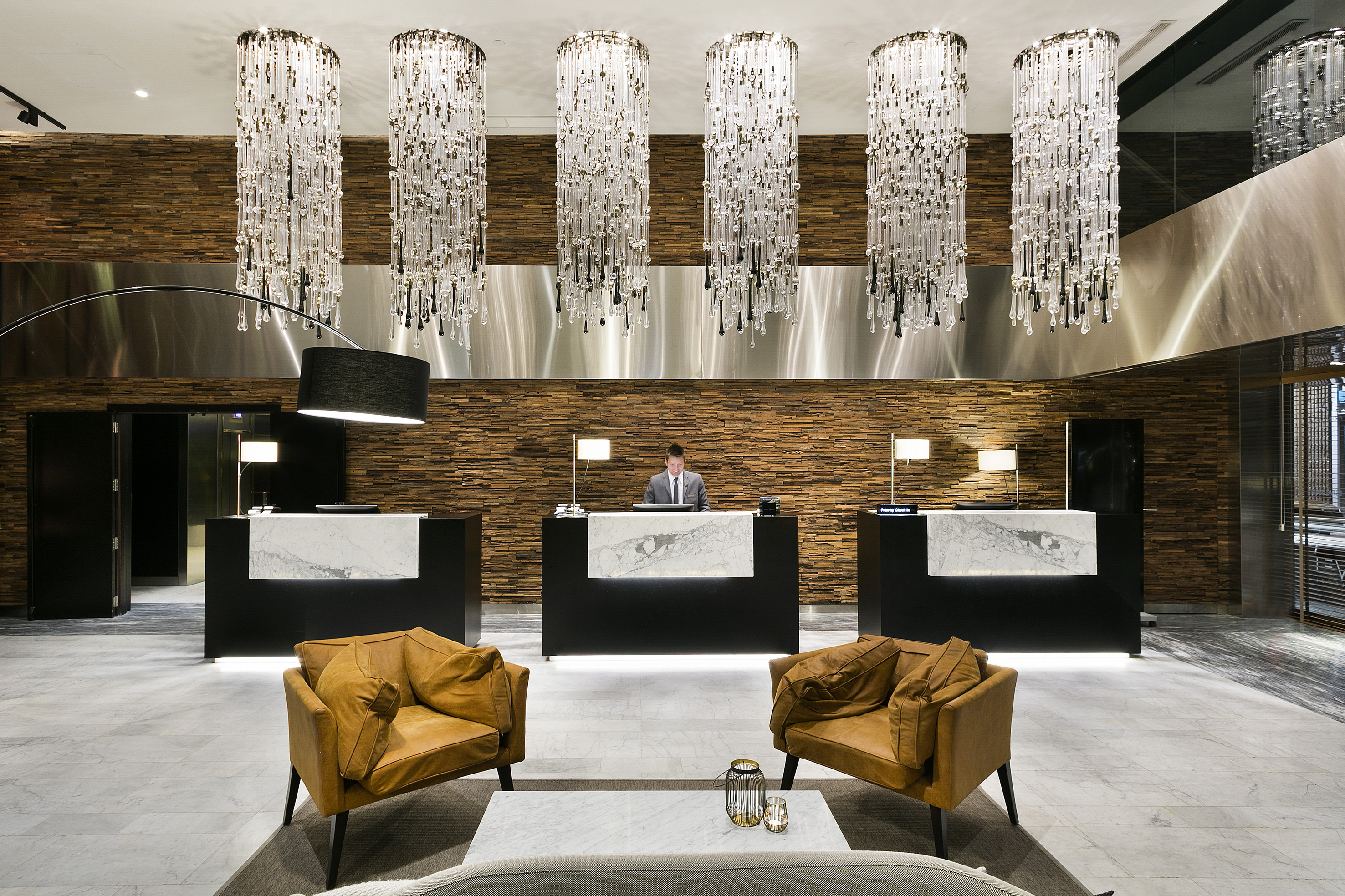 Elegant hotel lobby with crystal chandeliers, wood paneling, and front desk.