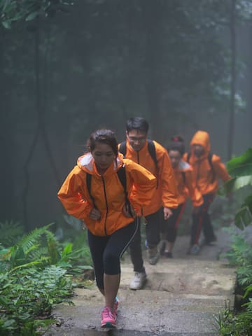 a group of people in orange jackets walking up a trail