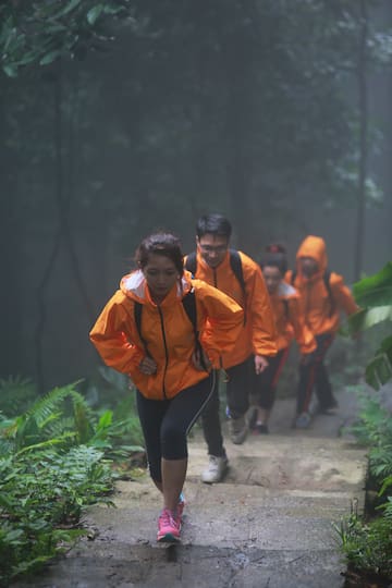 a group of people in orange jackets walking up a trail