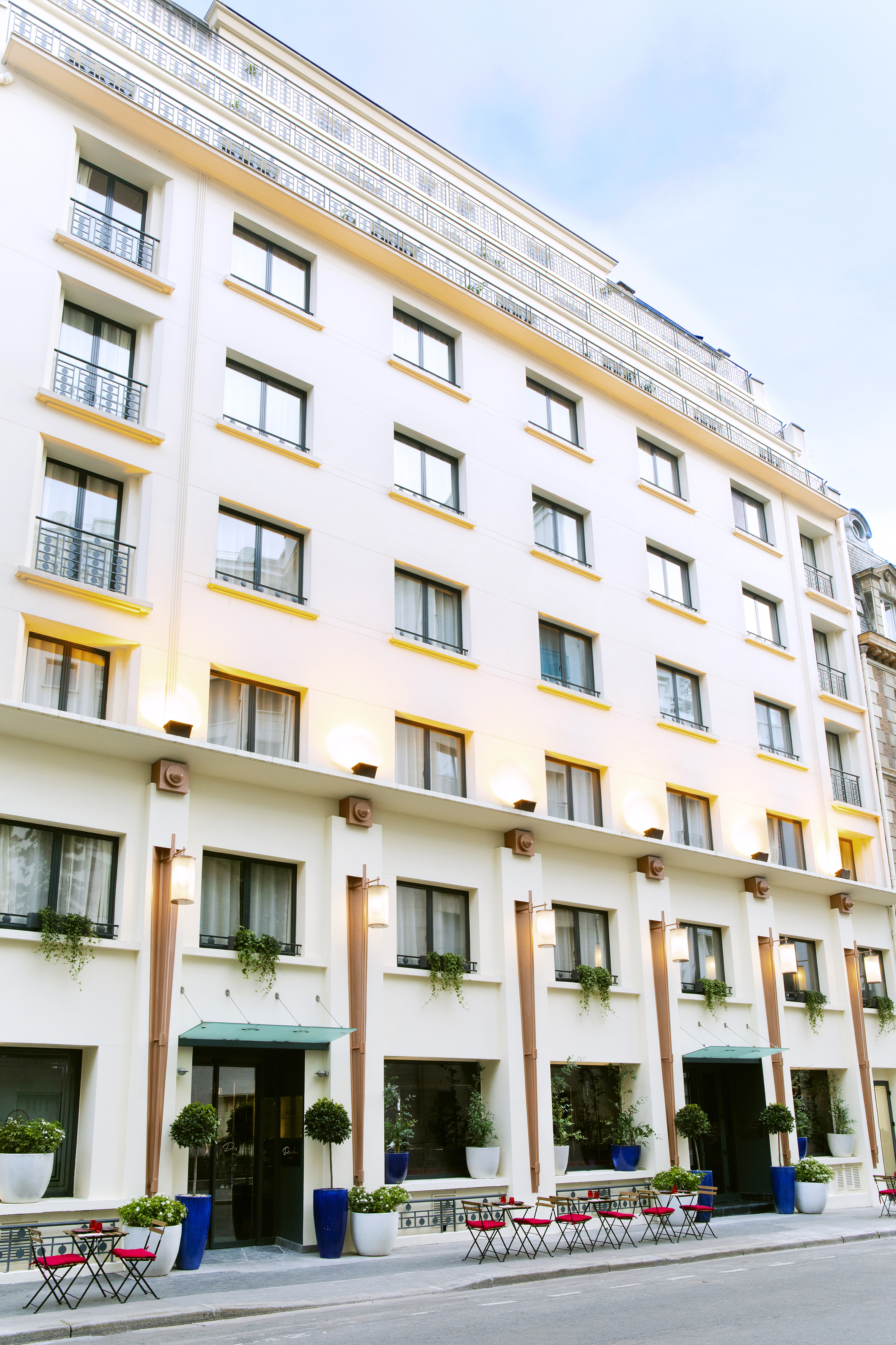 Elegant Parisian hotel facade, white building with balconies and outdoor cafe.