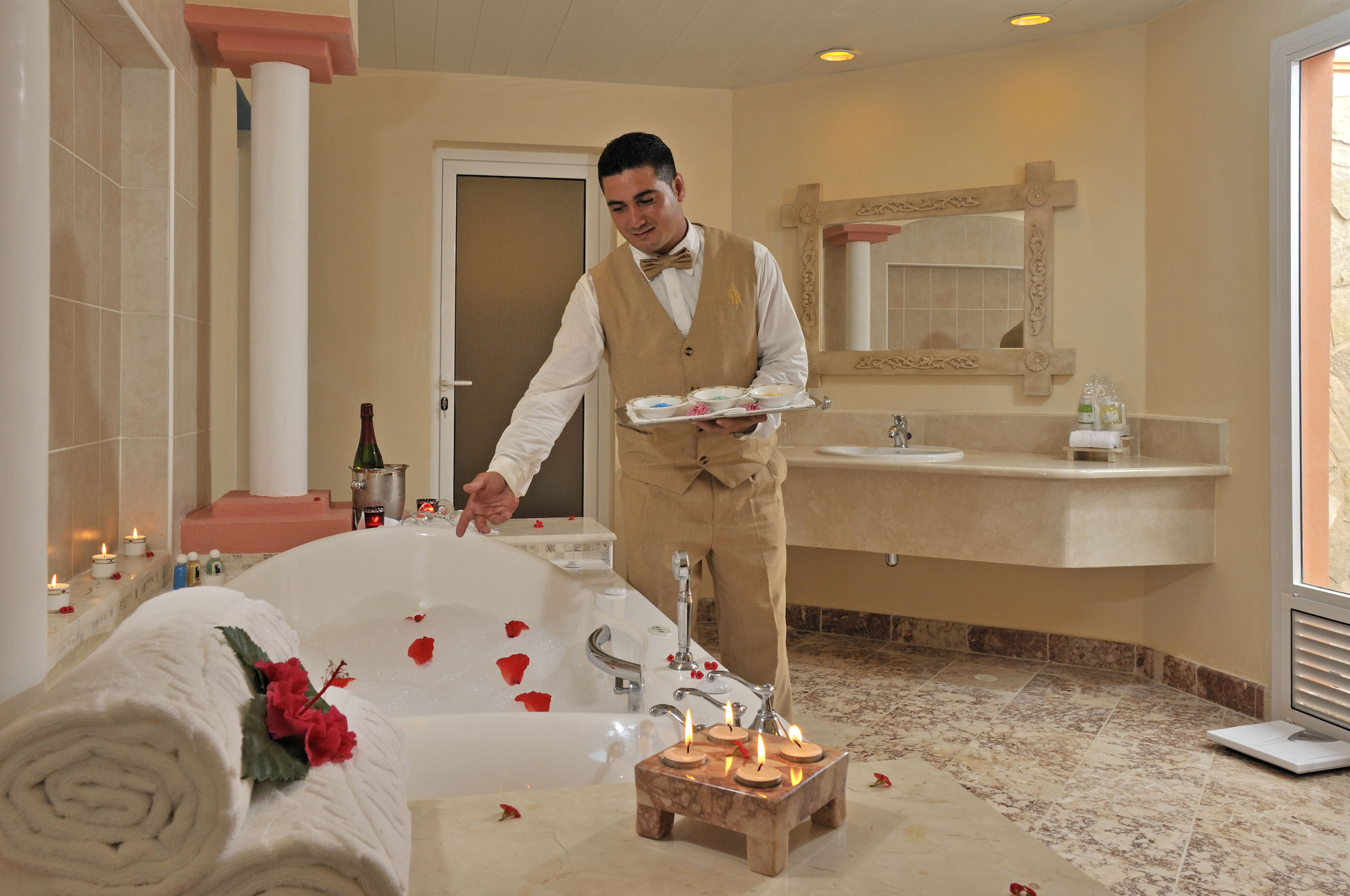 a man in a bathroom with a bathtub and rose petals