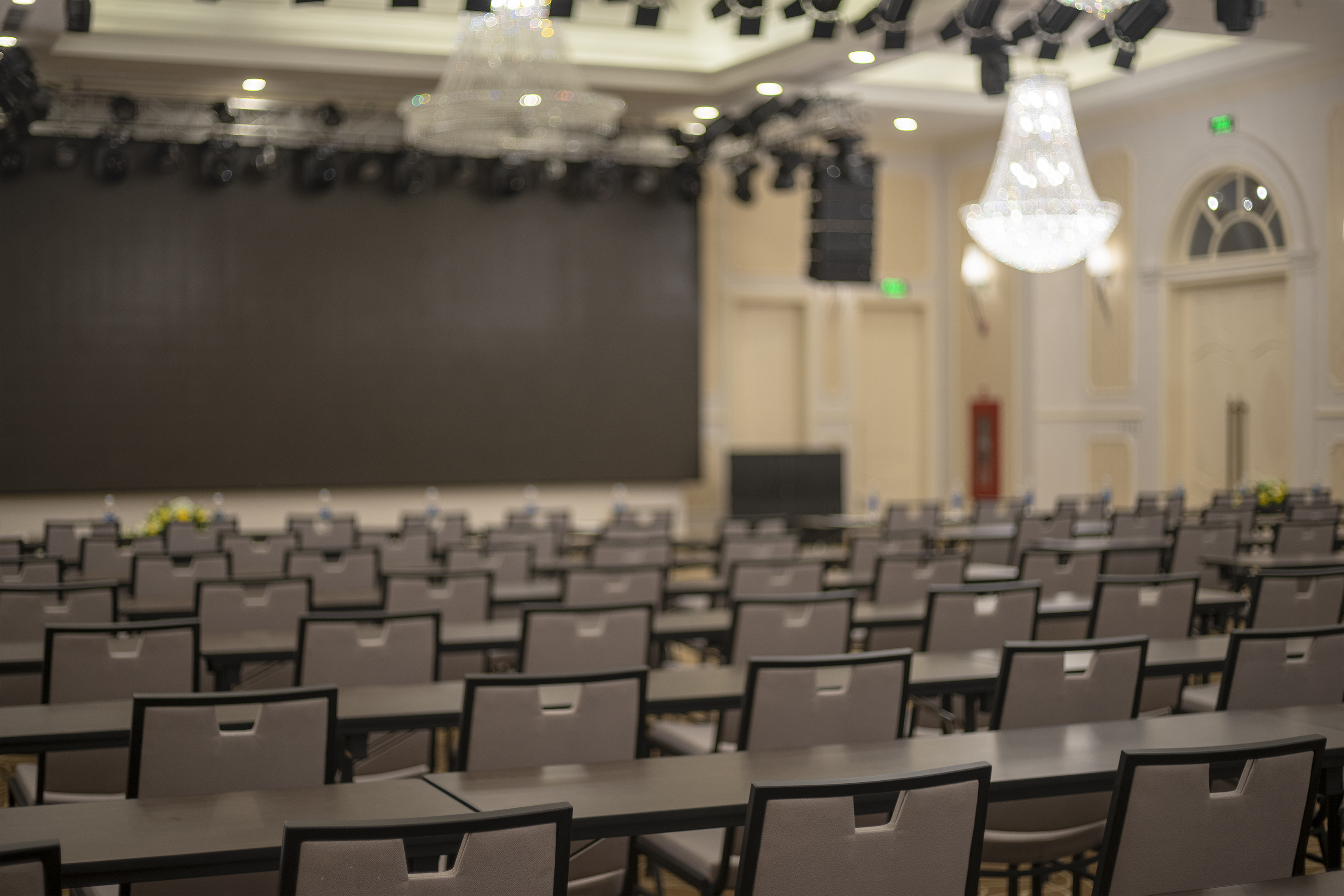 Convention hall setup with screen, stage, and rows of tables and chairs. - Ballroom A - Meliá Vinpearl Tay Ninh, Tay Ninh