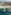 Aerial: beachfront resort, sandy beach, turquoise ocean, crescent breakwaters.