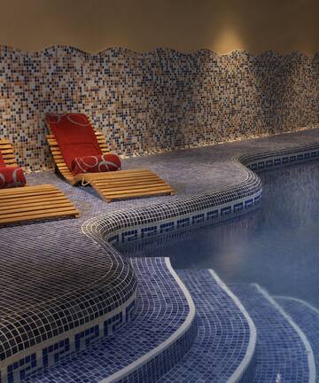 a pool with chairs and a tile wall