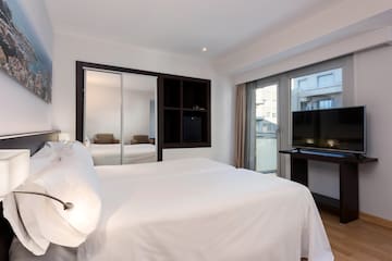 a bed with white sheets and a mirror in a room