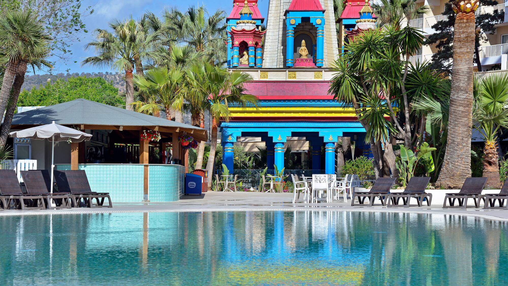 a pool with chairs and a building with a statue on it