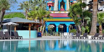 a pool with chairs and a building with a statue on it