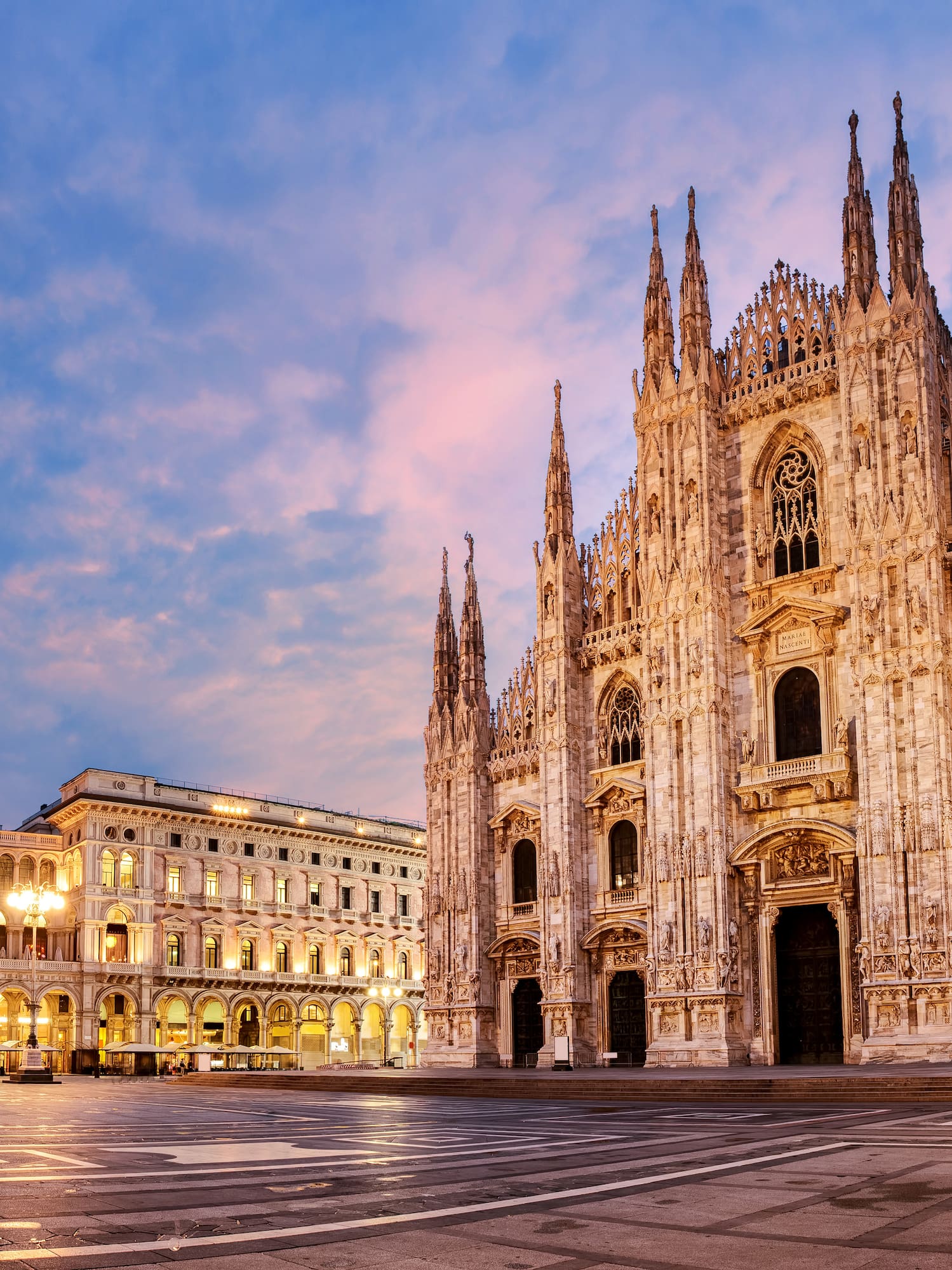 a large stone building with many windows with Milan Cathedral in the background
