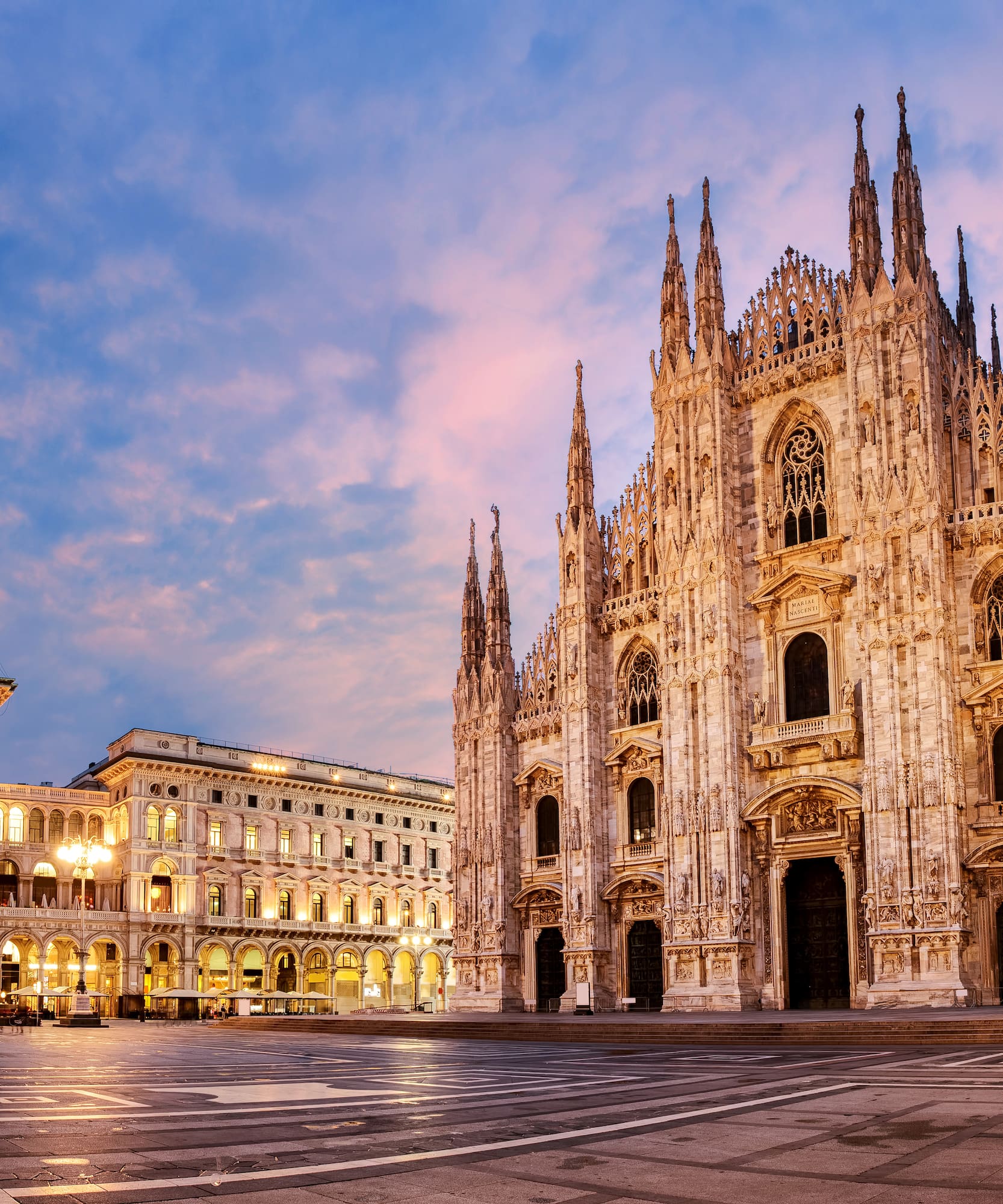 a large stone building with many windows with Milan Cathedral in the background