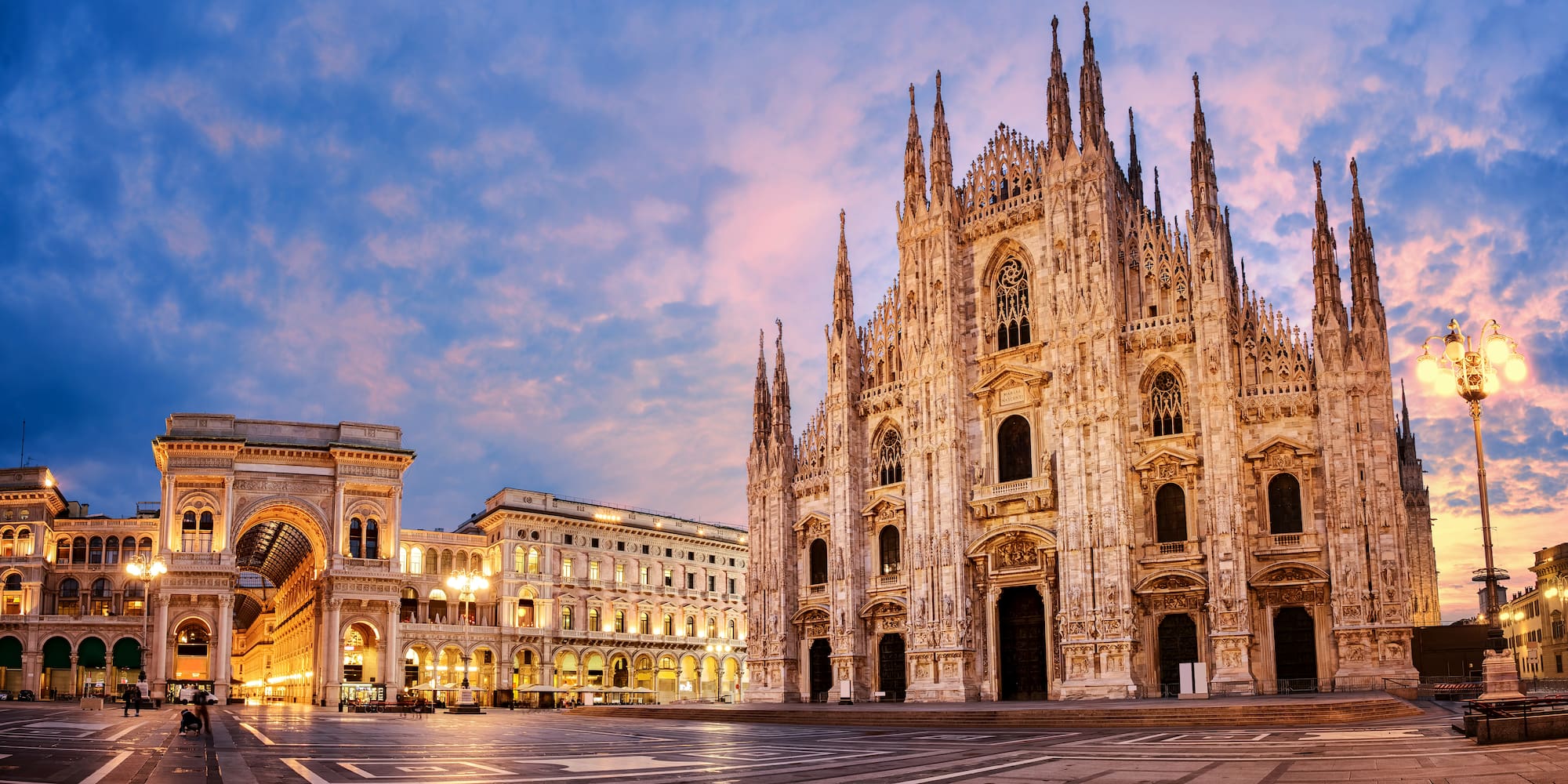 a large stone building with many windows with Milan Cathedral in the background