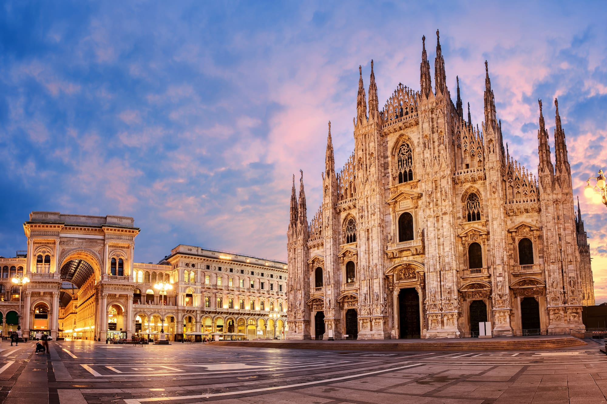 a large stone building with many windows with Milan Cathedral in the background