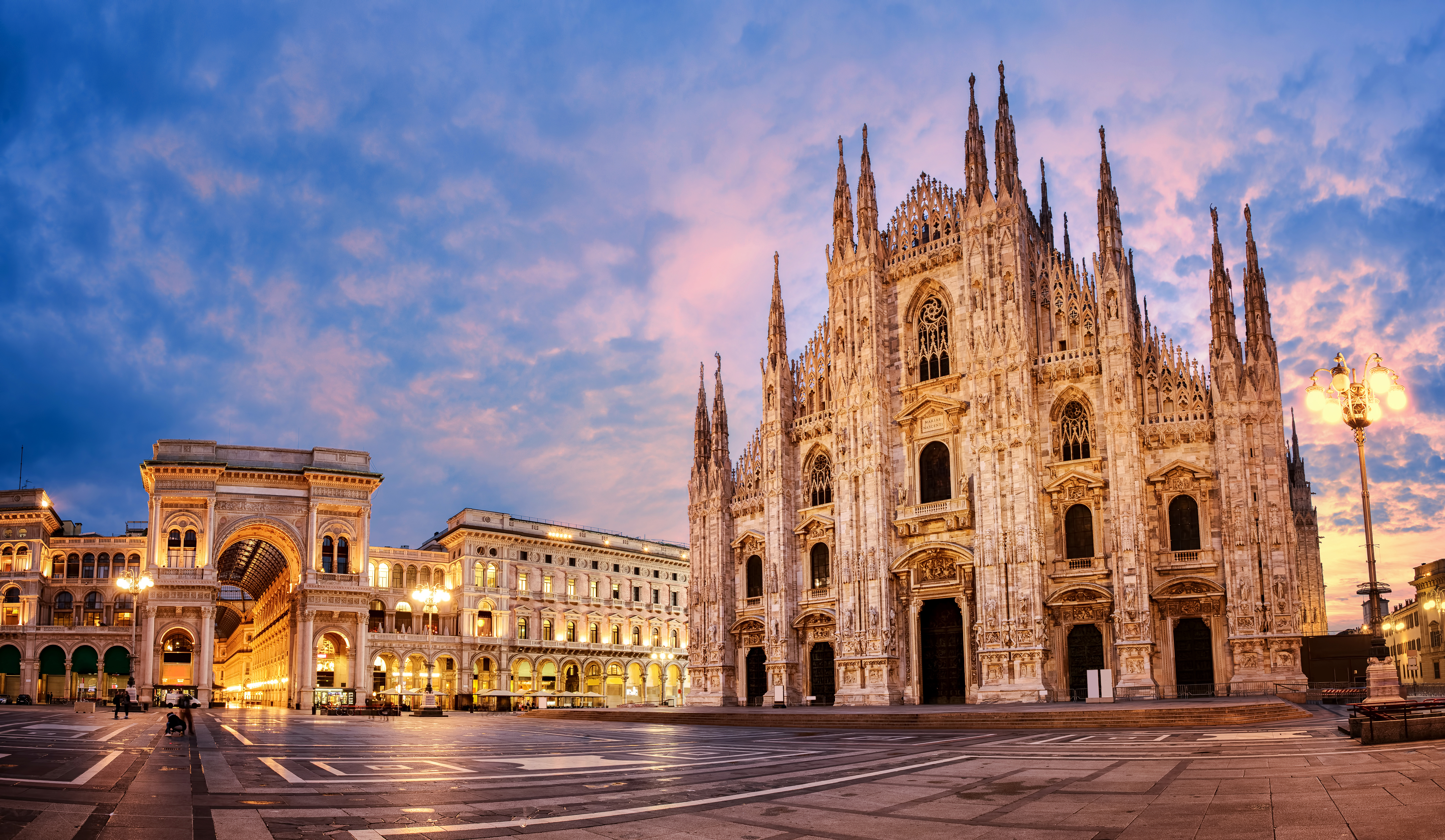 a large stone building with many windows with Milan Cathedral in the background