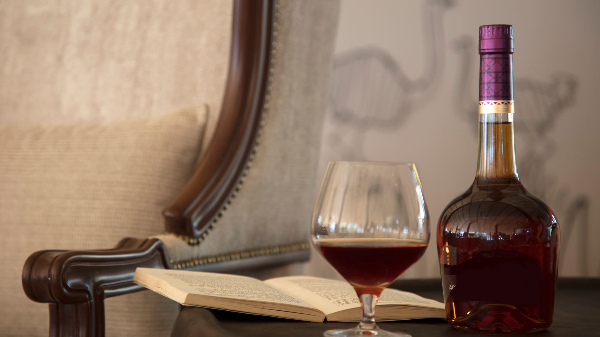 a bottle of liquid and a glass of wine on a table