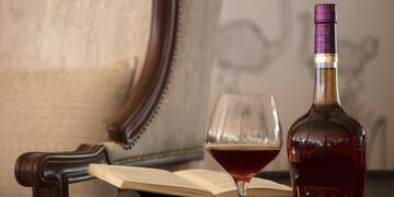 a bottle of liquid and a glass of wine on a table