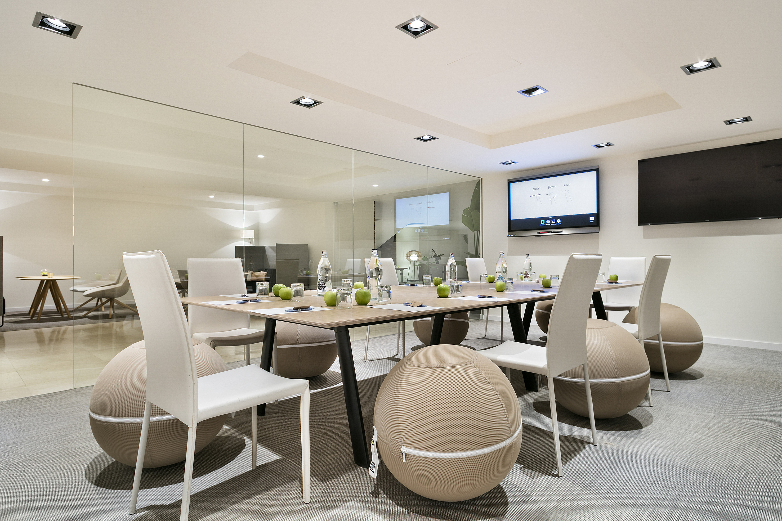 Modern meeting room with active seating chairs, glass partition, and display.