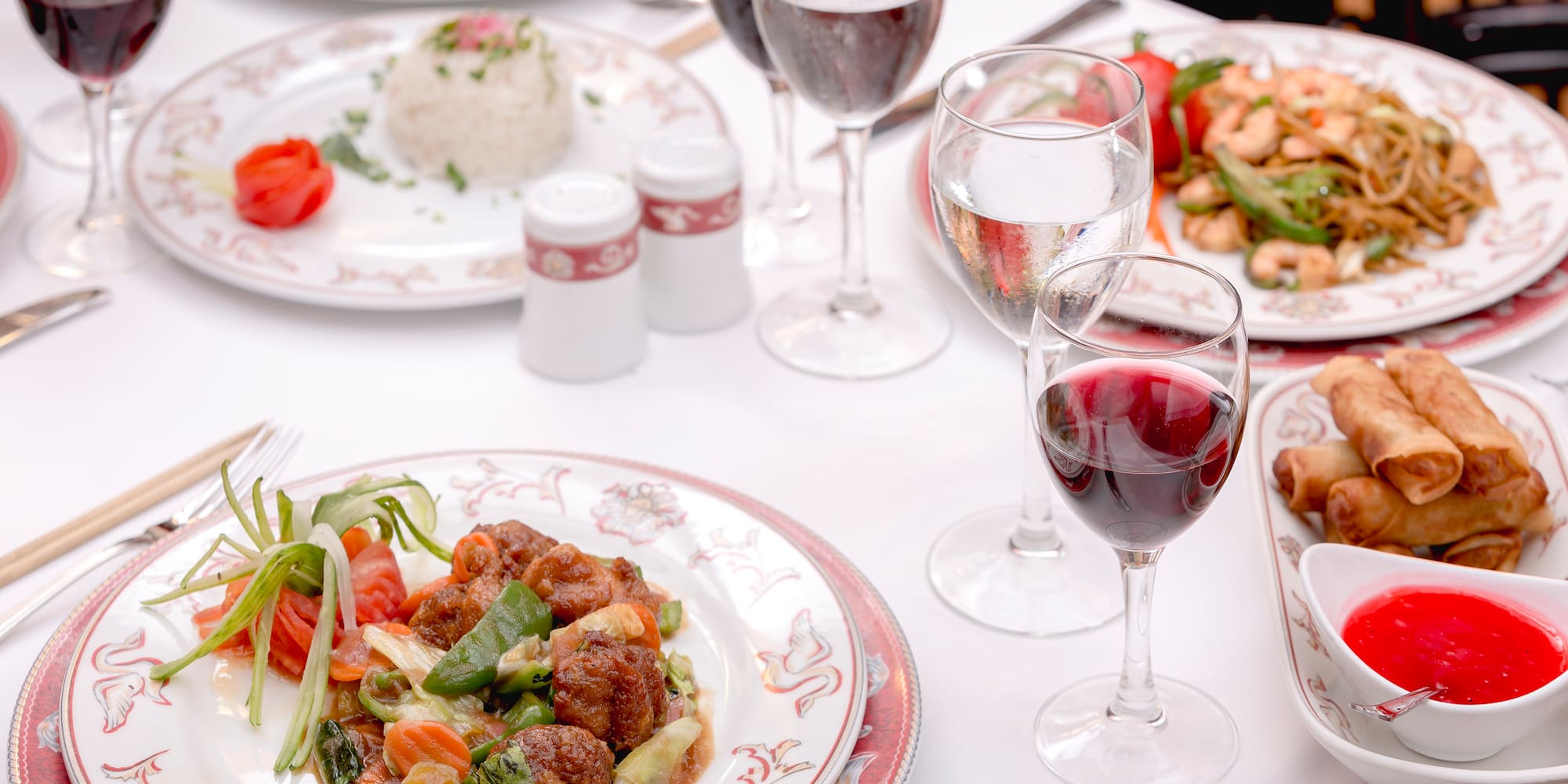 a table with plates of food and wine glasses